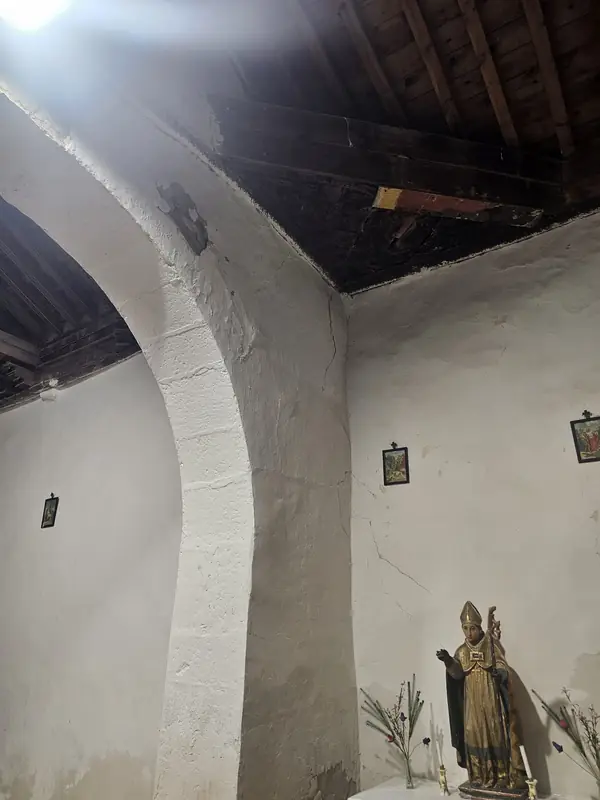 Arco interior de la nave con la imagen de un obispo dorado y los arcos de piedra