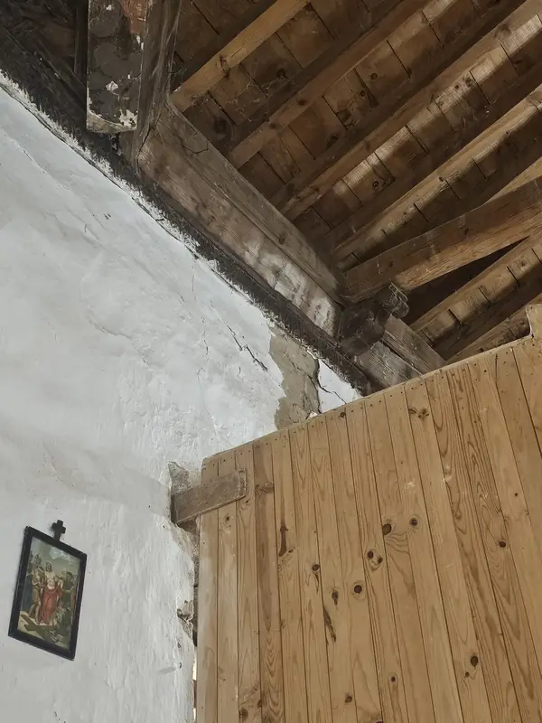 Interior del tejado mostrando vigas de madera deterioradas y paredes con humedad